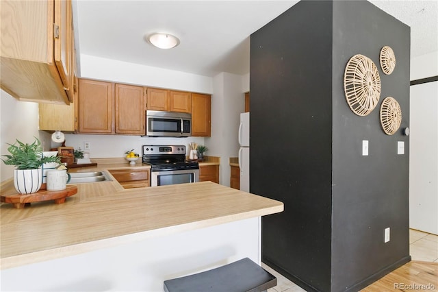 kitchen with appliances with stainless steel finishes, light countertops, and a peninsula