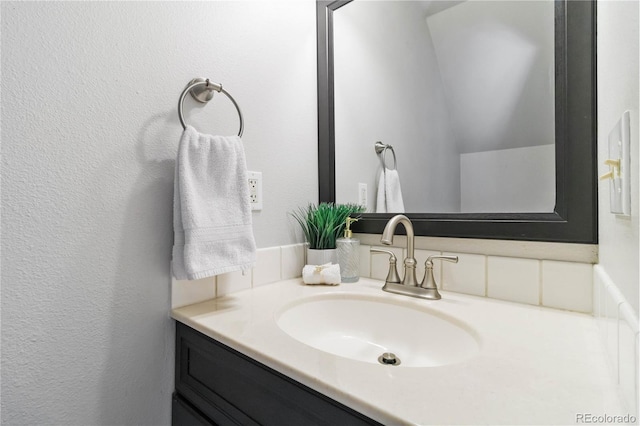 bathroom with a textured wall and vanity