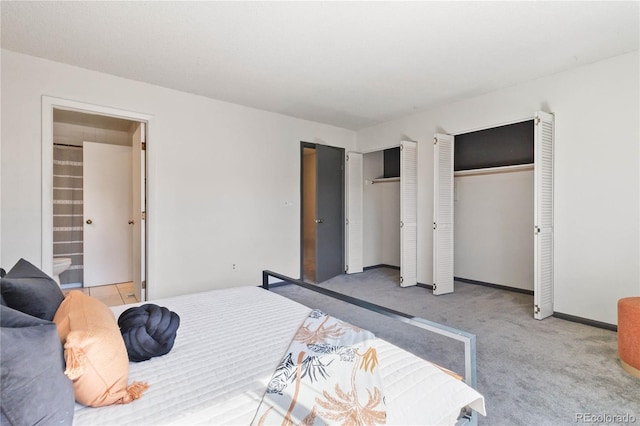 bedroom featuring carpet, connected bathroom, baseboards, and two closets