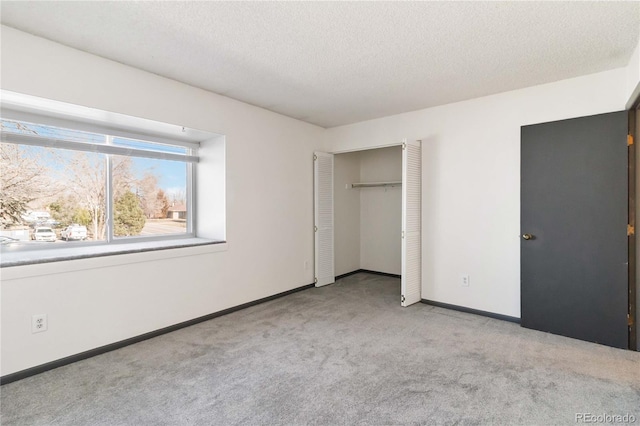 unfurnished bedroom with carpet floors, a closet, a textured ceiling, and baseboards