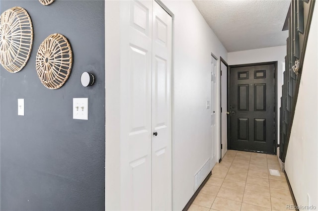 hall with light tile patterned floors and a textured ceiling