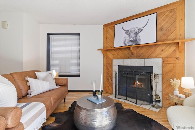 living room with a tile fireplace and wood finished floors