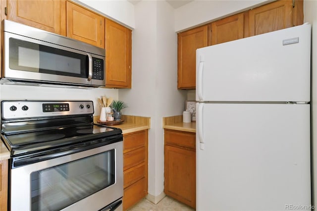 kitchen with stainless steel appliances, brown cabinetry, and light countertops