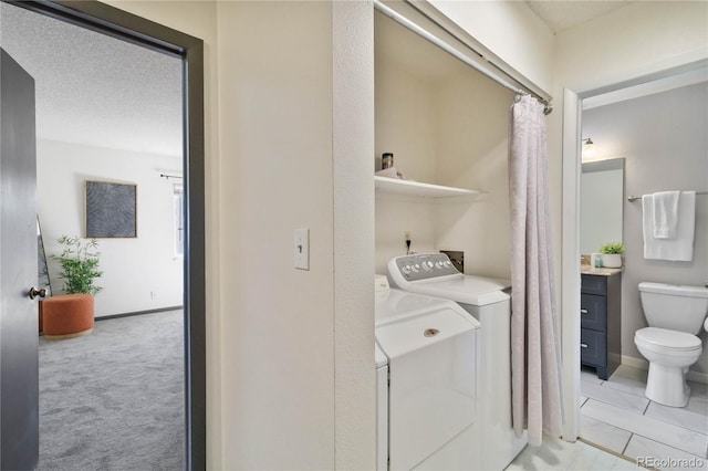 laundry area with washer and clothes dryer, light colored carpet, a textured ceiling, laundry area, and baseboards