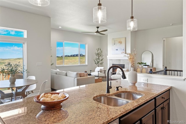 4011 W 149th Ave, Broomfield, CO 80023 - kitchen with ceiling fan, open floor plan, decorative light fixtures, a tiled fireplace, and light stone countertops