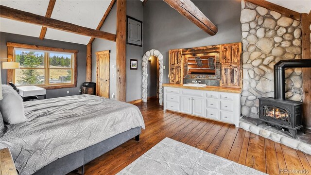 700 Cottage Grove Rd, Alma, CO 80420 - bedroom with a wood stove, wood-type flooring, beamed ceiling, baseboards, and high vaulted ceiling