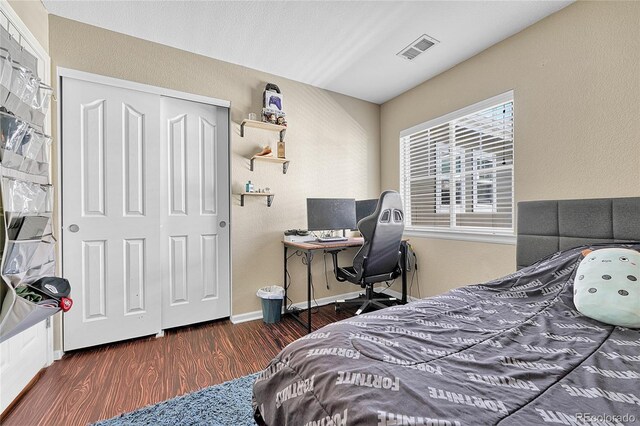 bedroom with visible vents, a textured wall, wood finished floors, and a closet