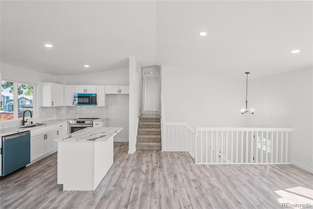 kitchen with white cabinetry, stainless steel appliances, vaulted ceiling, and a kitchen island