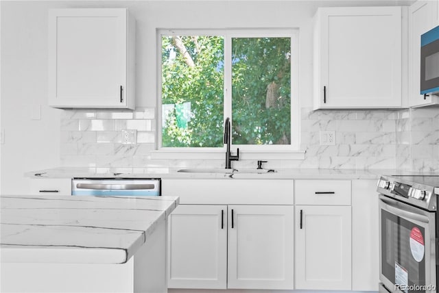 kitchen featuring white cabinets, tasteful backsplash, appliances with stainless steel finishes, light stone countertops, and sink