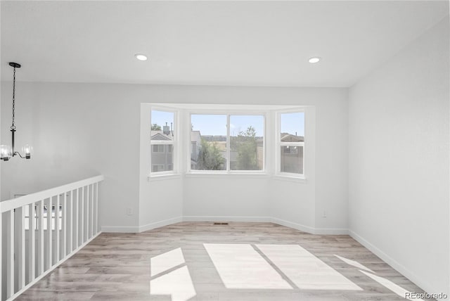 unfurnished room with an inviting chandelier and light wood-type flooring