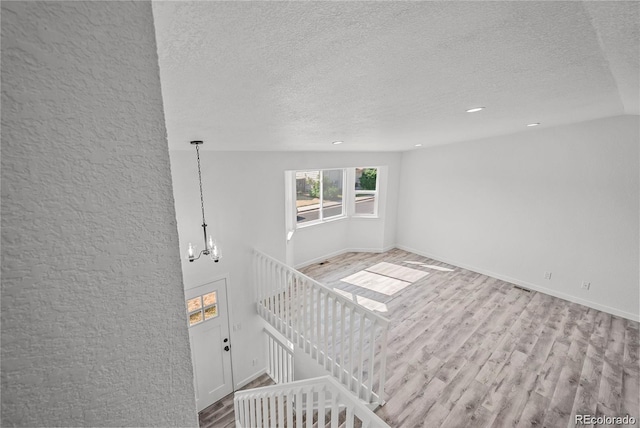 interior space featuring light hardwood / wood-style floors, an inviting chandelier, and a textured ceiling