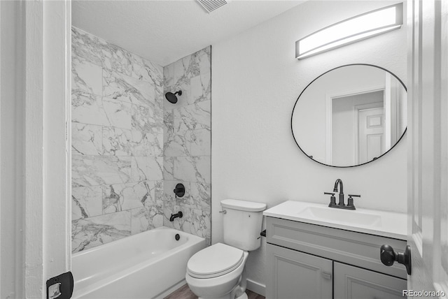 full bathroom featuring tiled shower / bath, vanity, a textured ceiling, and toilet