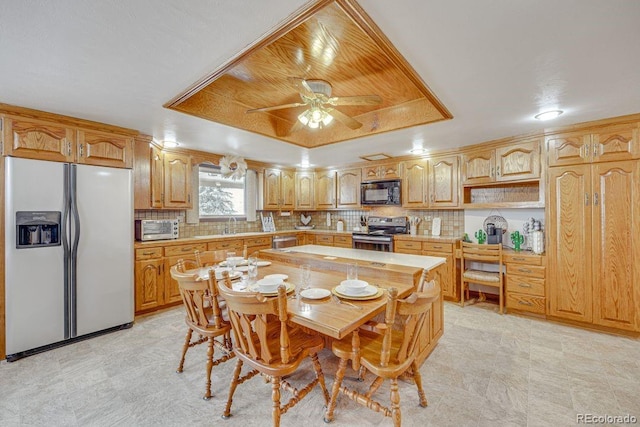 kitchen with sink, backsplash, stainless steel appliances, a center island, and a raised ceiling