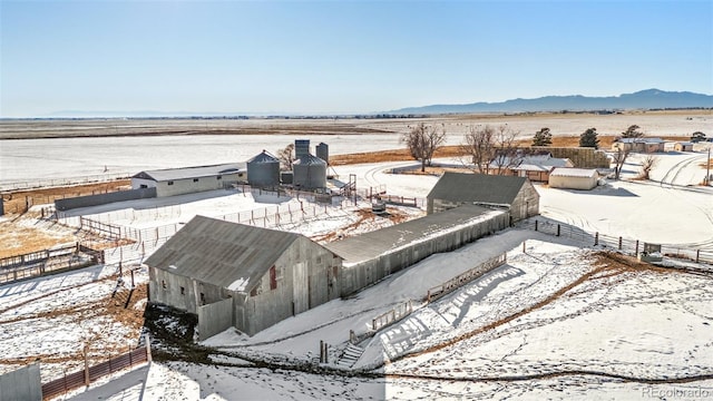 snowy aerial view featuring a rural view and a mountain view