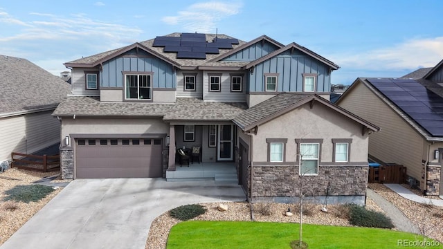 18541 W 93rd Pl, Arvada, CO 80007 - view of front of home featuring board and batten siding, roof mounted solar panels, an attached garage, stucco siding, and a shingled roof