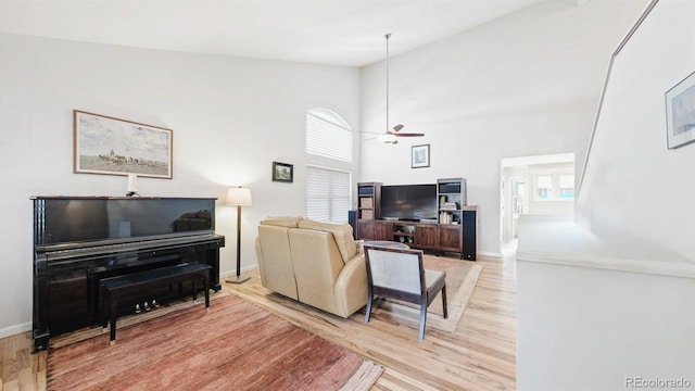 living room with light hardwood / wood-style flooring, high vaulted ceiling, and ceiling fan