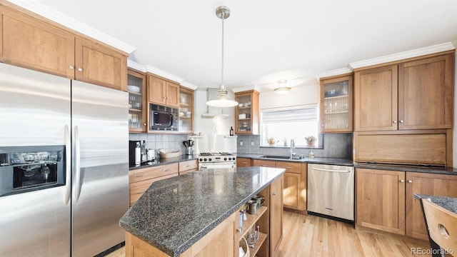 kitchen featuring pendant lighting, sink, stainless steel appliances, a center island, and dark stone counters