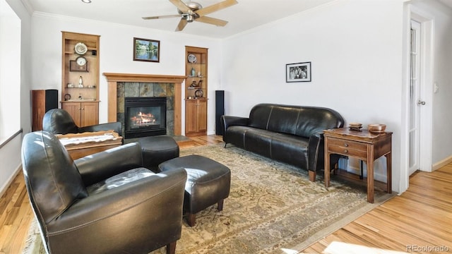 living room featuring crown molding, hardwood / wood-style floors, built in features, and a fireplace