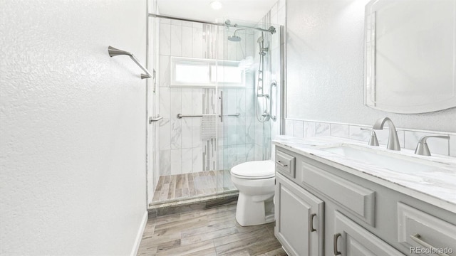 bathroom with hardwood / wood-style flooring, vanity, toilet, and a shower with shower door