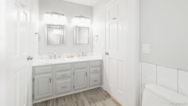 bathroom featuring vanity, toilet, and tile walls