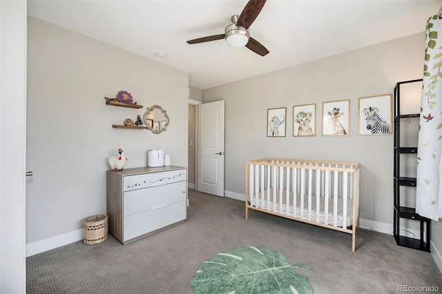 carpeted bedroom featuring ceiling fan and a nursery area