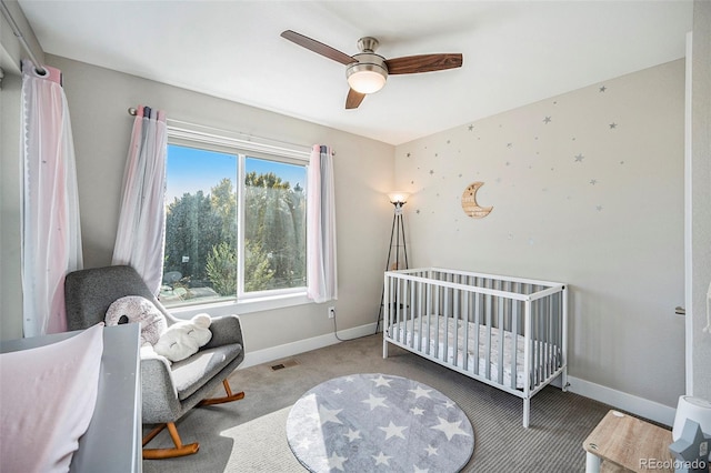 carpeted bedroom featuring a nursery area and ceiling fan