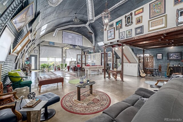 living area featuring a notable chandelier, high vaulted ceiling, and finished concrete flooring