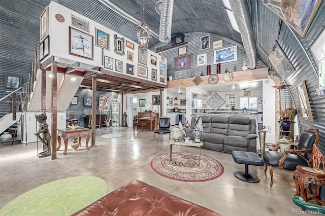 living room featuring decorative columns, high vaulted ceiling, finished concrete floors, and stairway