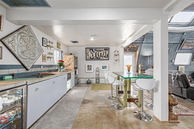 kitchen with light countertops, beverage cooler, visible vents, and concrete flooring