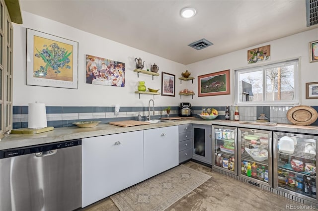 kitchen featuring a sink, open shelves, stainless steel dishwasher, and light countertops