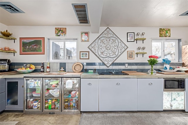 kitchen featuring built in microwave, visible vents, and light countertops