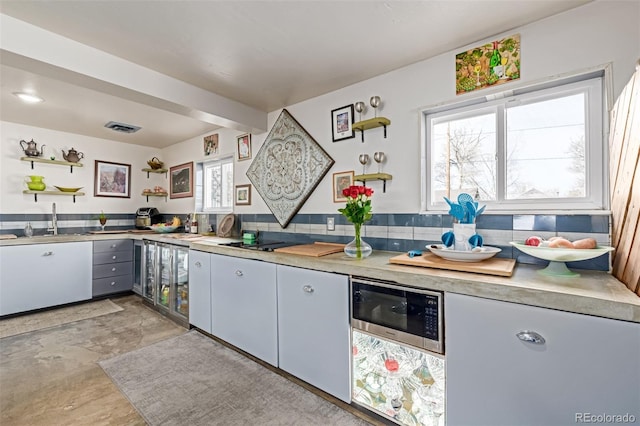 kitchen featuring decorative backsplash, open shelves, a sink, light countertops, and built in microwave