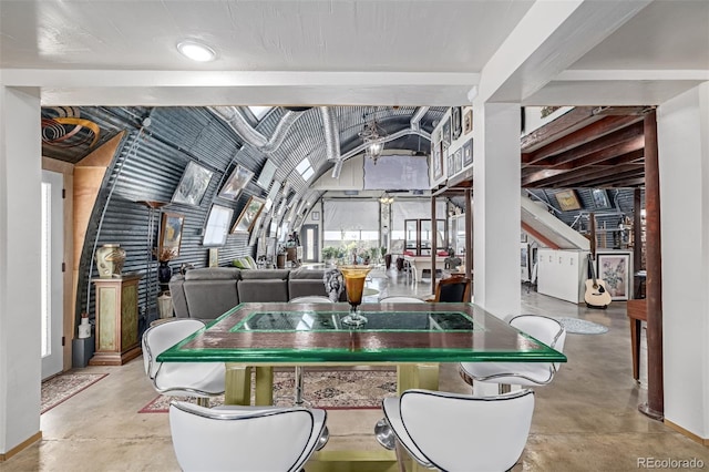 dining room featuring vaulted ceiling and finished concrete floors