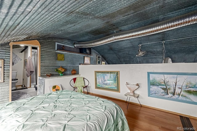 bedroom with baseboards, lofted ceiling, and wood finished floors