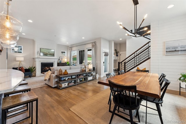 20998 E 60th Pl, Aurora, CO 80019 - dining area with wood finished floors, stairway, a chandelier, recessed lighting, and a warm lit fireplace