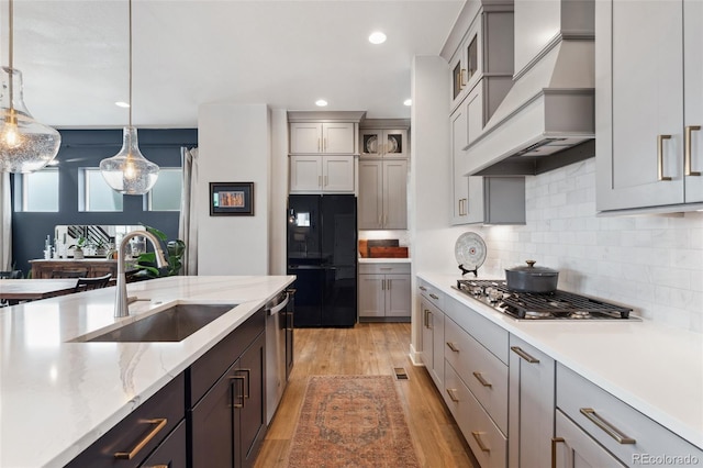 20998 E 60th Pl, Aurora, CO 80019 - kitchen featuring freestanding refrigerator, custom range hood, stainless steel gas cooktop, light wood-type flooring, and tasteful backsplash