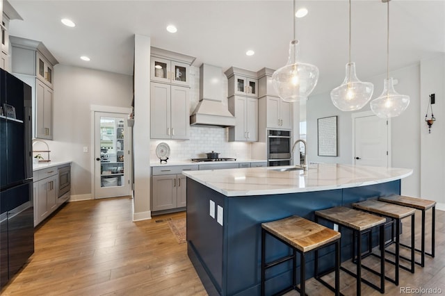 20998 E 60th Pl, Aurora, CO 80019 - kitchen with custom exhaust hood, light wood-type flooring, a breakfast bar, backsplash, and recessed lighting