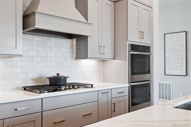 20998 E 60th Pl, Aurora, CO 80019 - kitchen with premium range hood, appliances with stainless steel finishes, gray cabinetry, light countertops, and decorative backsplash