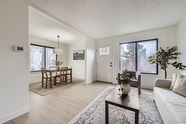 living area with baseboards, light wood finished floors, and a textured ceiling