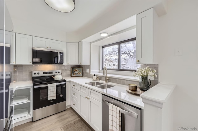 kitchen with a sink, stainless steel appliances, tasteful backsplash, and white cabinetry