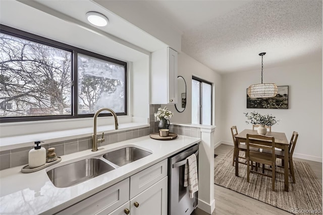 kitchen featuring white cabinetry, a sink, light countertops, dishwasher, and light wood-type flooring