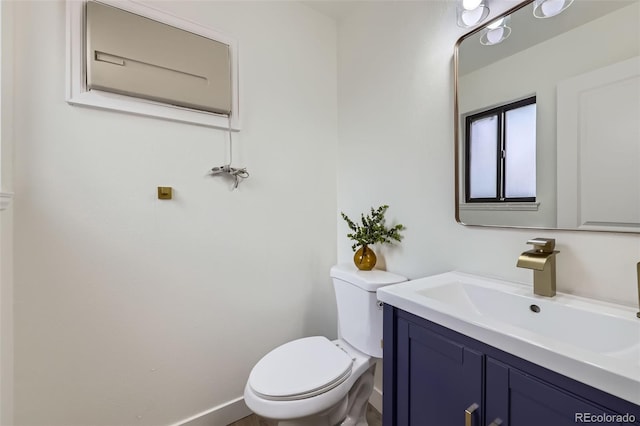 half bathroom featuring toilet, vanity, and baseboards