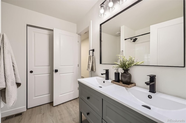 bathroom featuring double vanity, visible vents, wood finished floors, and a sink