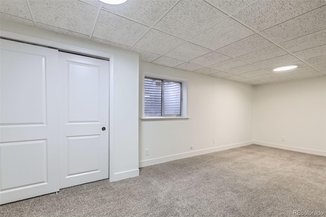 unfurnished bedroom with a paneled ceiling, baseboards, and carpet floors