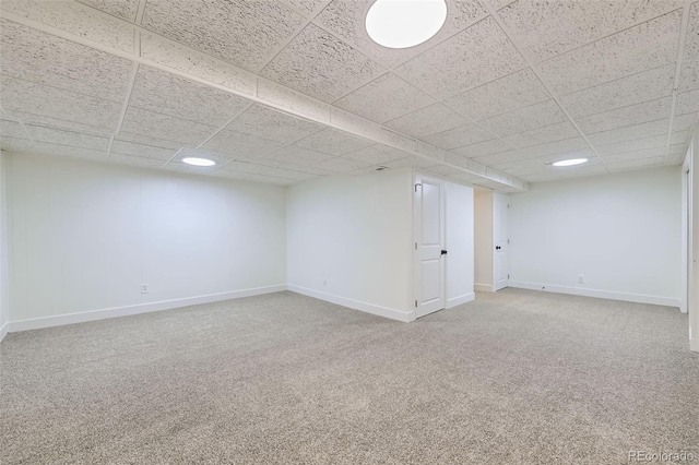 finished basement with a drop ceiling, baseboards, and carpet