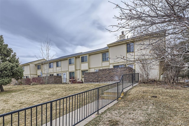 rear view of house featuring stucco siding and fence