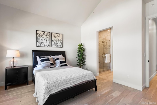 bedroom featuring light wood-type flooring, vaulted ceiling, and ensuite bath