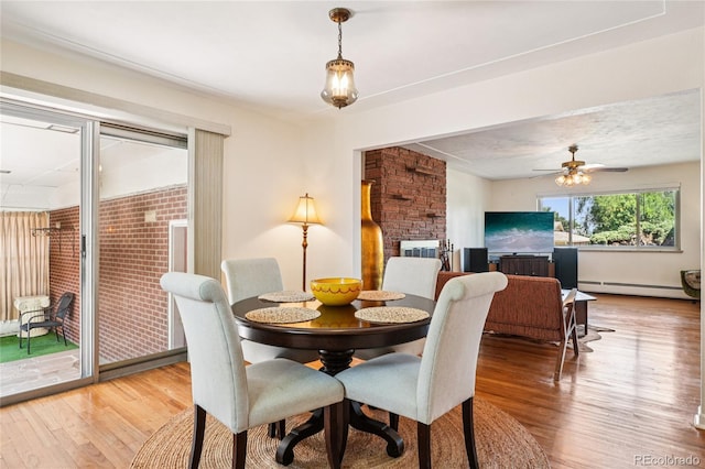 6920 W 47th Pl, Wheat Ridge, CO 80033 - dining room featuring wood finished floors, a baseboard heating unit, a ceiling fan, and a fireplace