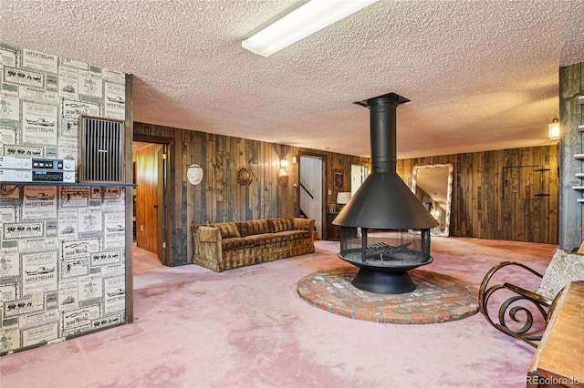 6920 W 47th Pl, Wheat Ridge, CO 80033 - carpeted living room featuring wooden walls, a textured ceiling, a wood stove, and stairs
