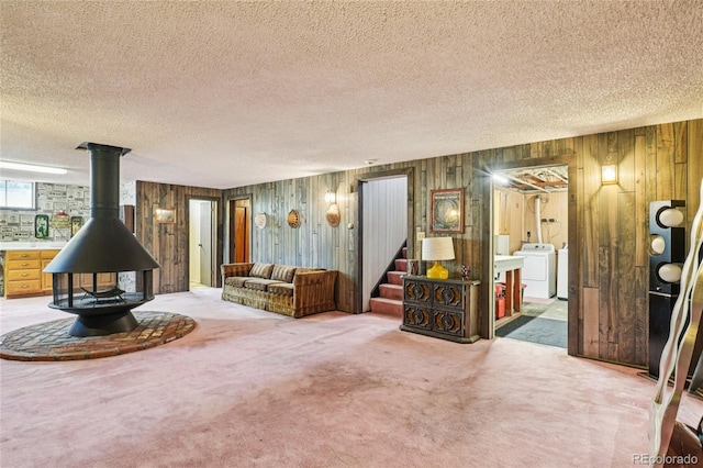 6920 W 47th Pl, Wheat Ridge, CO 80033 - carpeted living room featuring a wood stove, stairs, washer / clothes dryer, a textured ceiling, and wooden walls